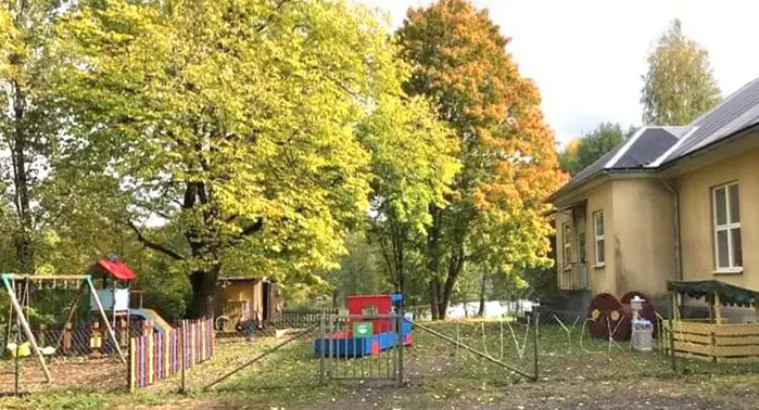 Lummiga träd vid skolgård och ljusbrun byggnad